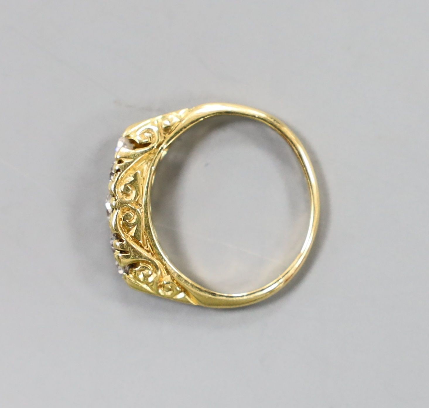 An early 20th century 19ct gold and graduated five stone diamond set half hoop ring, size G, gross weight 2.8 grams.